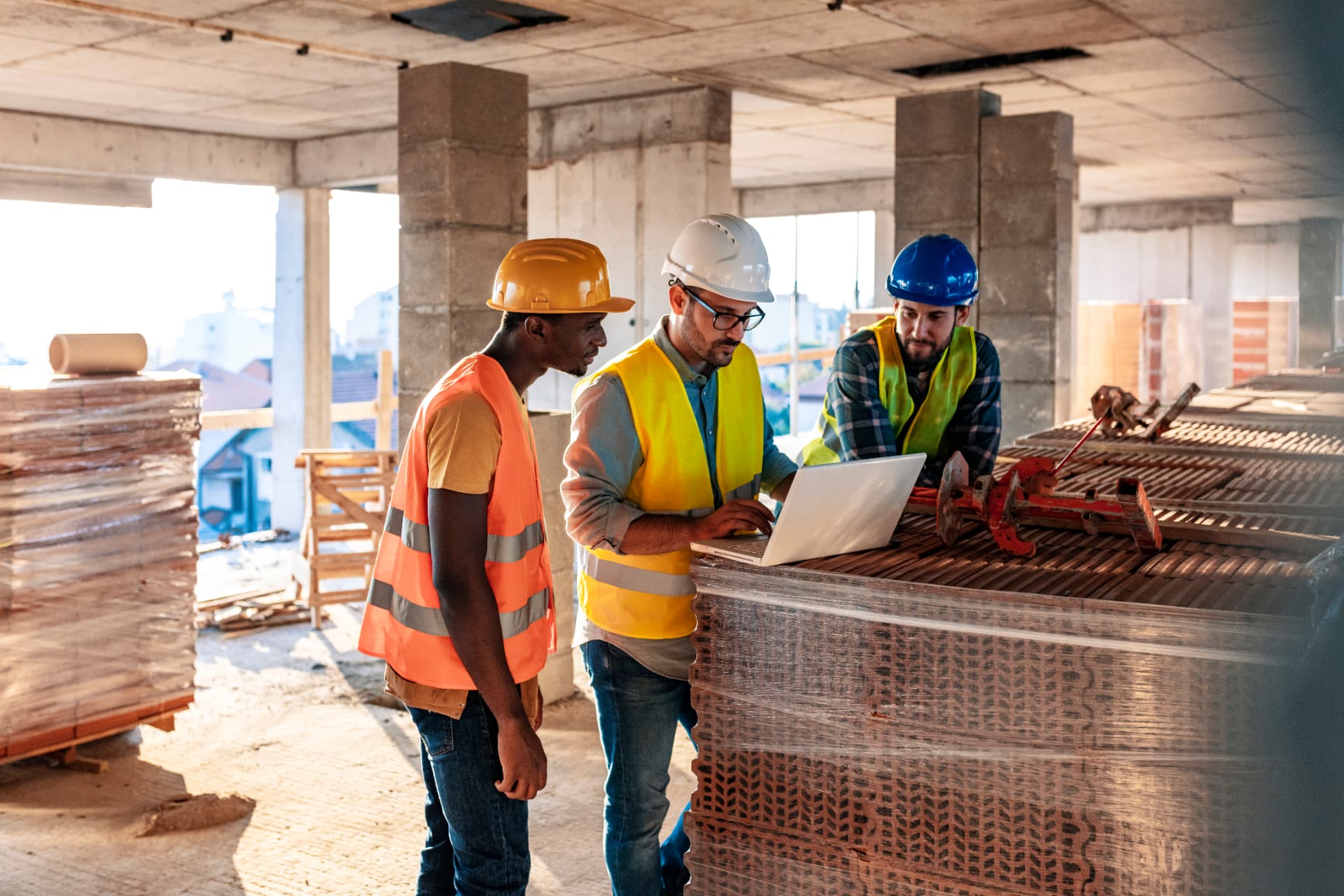 Three contractors reviewing plans on a laptop at a job site